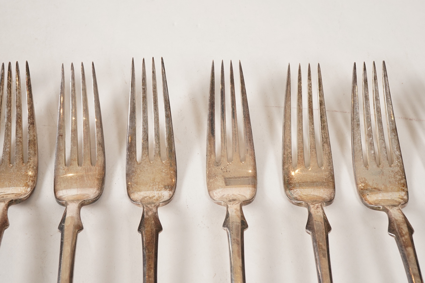 A set of twelve white metal fiddle and shell pattern table forks and five matching dessert forks